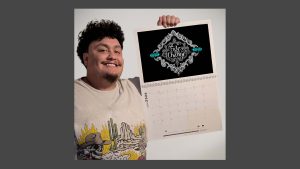 Brant holding the 2026 calendar with his artwork showing