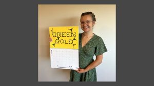 Daniélle holding up the 2026 calendar with her artwork showing