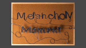 2026 calendar artwork with text "Melancholy Moment" written with yarn treaded around thumb tacks