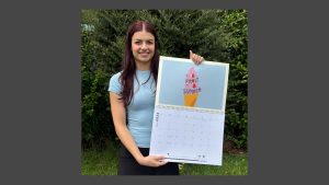 Lisa holding 2026 calendar with her artwork